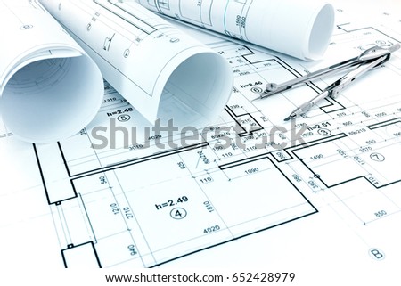 rolls of blueprints, drawing compass and graphical architectural plan of apartments