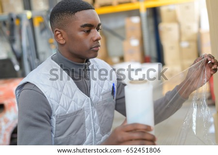Warehouse worker holding roll of shrink wrap