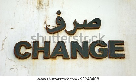 "Change" written in two different languages with old / rusty letters on a white old wall / copy-space