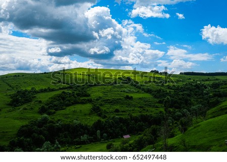 moving shadows over green meadows and hills with shrubs, bushes, trees and blue sky white clouds in the spring / East European scenery - Transylvania region / lights and shadows