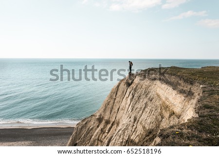 Bovbjerg strand in Denmark, steep cliff and human standing on the edge, dangerous beautiful view on the ocean