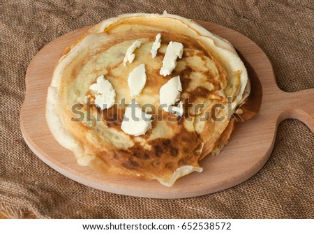 Stack of homemade pancakes with butter on wooden board