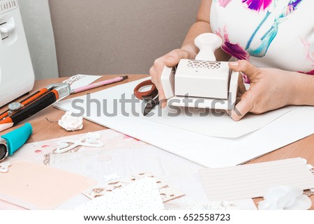 Tools for scrapbooking. A woman uses tools to cut paper.