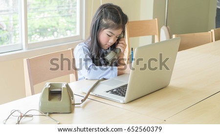 Asian school girl holding telephone and writing note in a room