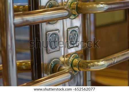 Gold color brass entrance doors showing large grab handles and a PUSH sign with patina