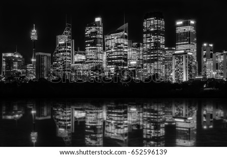 Beautiful Sydney Skyline at night in black and white of Central Business District seen from Farm Cove, with reflections in bay's water.