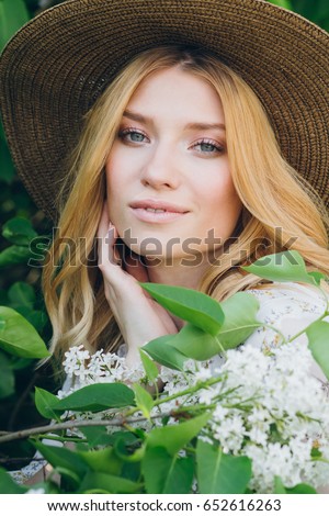 Young beautiful blond woman with lilac flowers in the spring. Portrait. Toning.