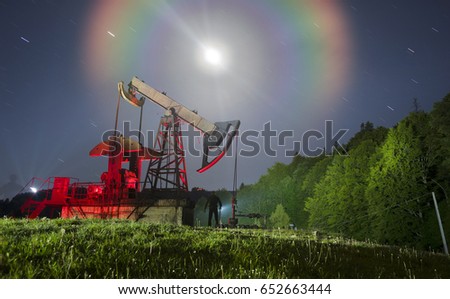  ancient traditional classic oil pumps of Ukrainian oilmen in the Carpathian Mountains on the Delyatyn Polonium are illuminated by colored LED flashlights under the starry sky of the Galaxy
