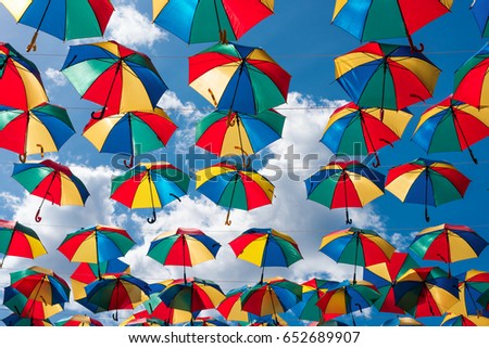 Colorful umbrellas background. Summer festival urban street decoration. Hanging Multicoloured umbrellas over blue sky.