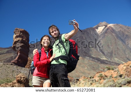 Couple taking picture having fun outdoors on vacation on Tenerife, Canary Islands. The volcano Teide and the famous Garcia Rock in the background. Young beautiful couple.