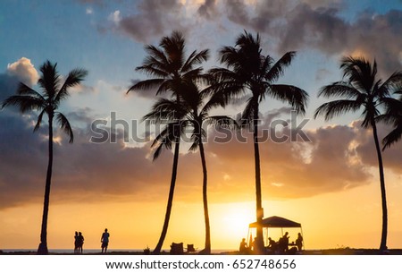 Sunset palm beach with people's silhouettes.