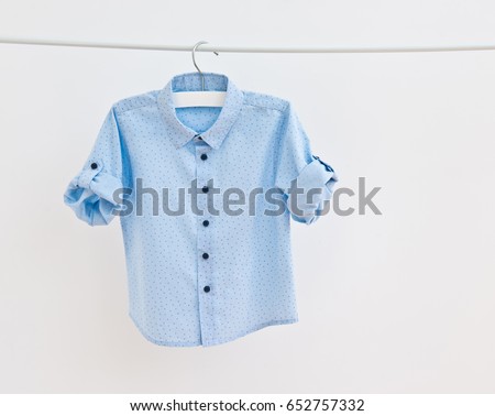 Fashion blue baby-boy shirt hanging on a clothesline isolated on white background/ Baby clothes/ Close-up. Royalty-Free Stock Photo #652757332