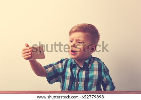 Serious caucasin child using smartphone
