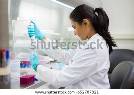 Closeup portrait, scientist pipetting from 50 mL conical tube with blue liquid solution, performing laboratory experiments, isolated lab . Forensics, genetics, microbiology, biochemistry Royalty-Free Stock Photo #652787821