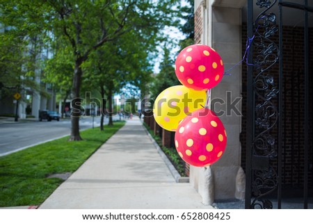 Beautiful red and yellow balloons with polka dots on them float in the wind on a Chicago neighborhood city street.
