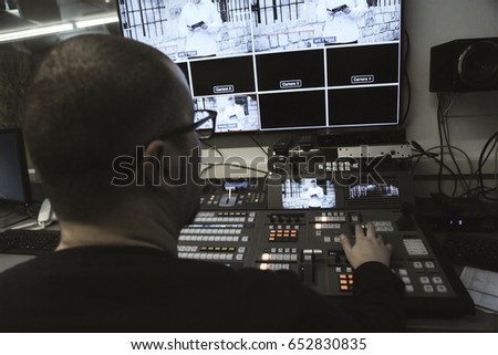 TV editor working with audio video mixer in a television broadcast studio desk station