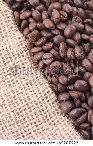 close up of dark roasted fair trade coffee beans on jute covering diagonal half of the picture