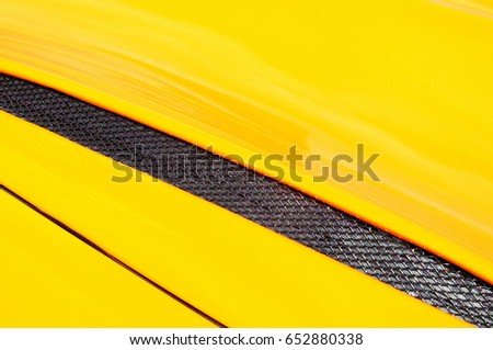 Yellow glossy surface of the car's hood, air intake grille. abstract background. Photo partially toned