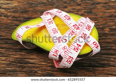 Avocado with measurement tape healthy food.on wood.