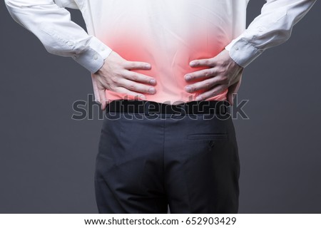 Back pain, kidney inflammation, ache in man's body close-up on gray background with red dot Royalty-Free Stock Photo #652903429