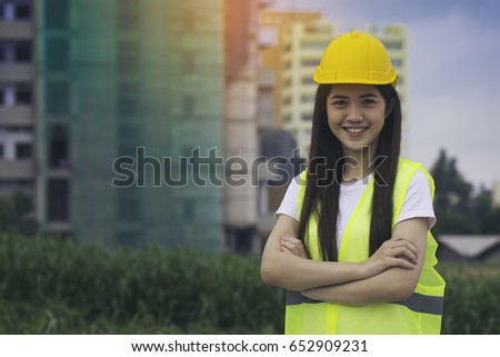 Engineers pretty girl standing arms crossed and smiling happily after successfully building construction.