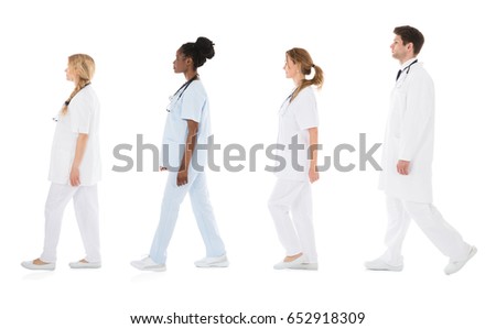 Multiracial Medical Team Walking In Row In Front Of White Background