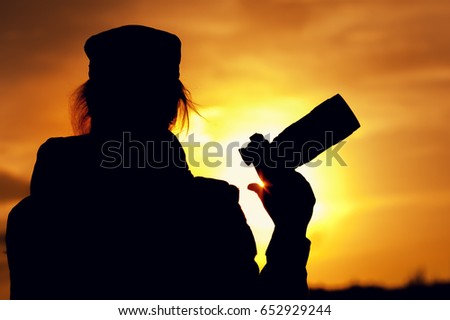 Silhouette of female photographer against sunset