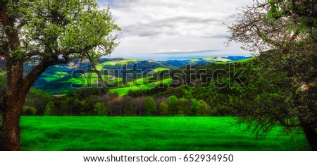 Fine art scenic colorful idyllic spring landscape panorama of a rural countryside in Austria with trees,forest,fields,hills,valleys,farm and a view towards the horizon