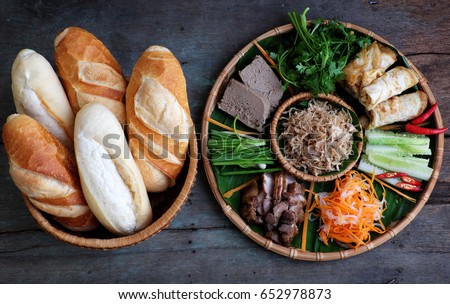 Famous Vietnamese food is banh mi thit, popular street food from bread stuffed with raw material: pork, ham, pate, egg and fresh herbs as scallions, coriander, carrot, cucumber, chilli. Royalty-Free Stock Photo #652978873