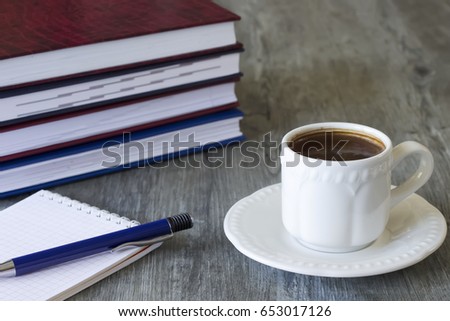 Business concept. Objects on gray background. A white cup of coffee, notebooks  and pen. Soft focus.  Horizontal. 