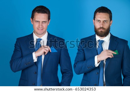 businessman or man in suit putting different business cards in pockets on blue background. Happy, smiling, shaven face on left and confident, serious with beard on right. Contrast, business etiquette
