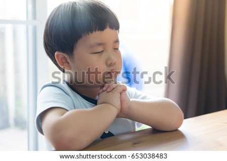 A little boy is praying in the morning.