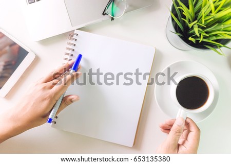 Office atable with blank notebook and laptop / Coffee cup