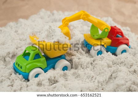 toy excavator is loading of heavy dump-body track by sand. Construction, mining, construction equipment at work