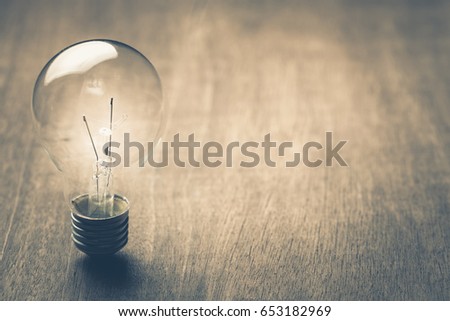 Glowing light bulb on wood background