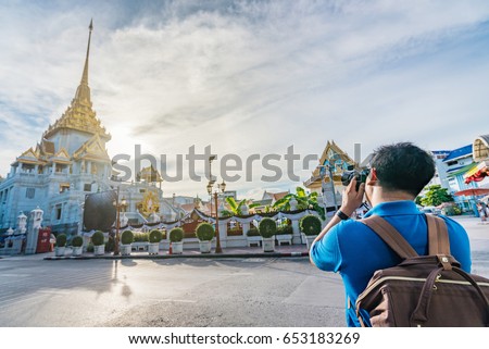 Young Asian traveler taking photo with camera at Wat Trimitr it's located near china town or Yaowarat in Bangkok, Thailand.