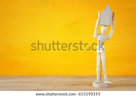 Wooden dummy holding house model. Real estate concept