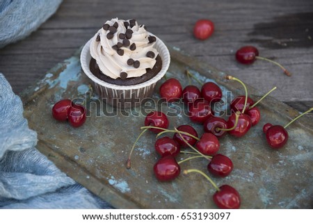 Chocolate capcake and cherry on an old background