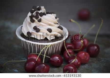 Chocolate capcake and cherry on an old background
