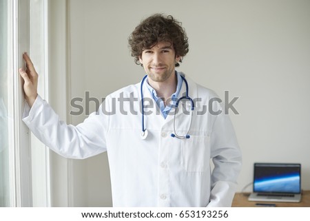 Shot of a young male doctor standing in doctor's room while waiting for patient. 