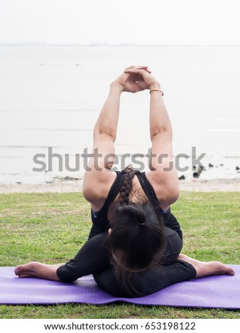 Asian  young woman wearing black shirt practicing Yoga on the purple seat