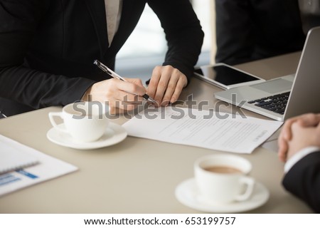 Close up of female hand holding pen, about to sign official paper, putting signature on legal document, ink deal, enter conclude contract for services, work and supplies, bilateral basic agreement  Royalty-Free Stock Photo #653199757