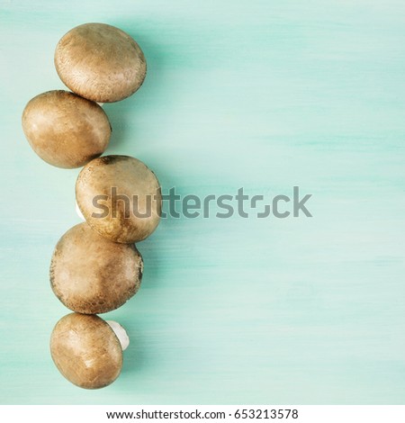 A square overhead photo of portobello mushrooms with a place for text on a teal wooden texture
