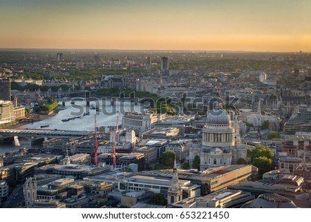 Stunning aerial view of St. Paul Cathedral, the city skyline and the river Thames against the evening orange sky at dusk in London, England, UK
