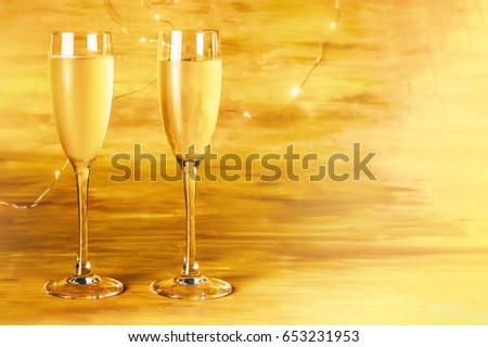 A side view of two glasses of champagne on a blurred golden background with shining lights, with a place for text