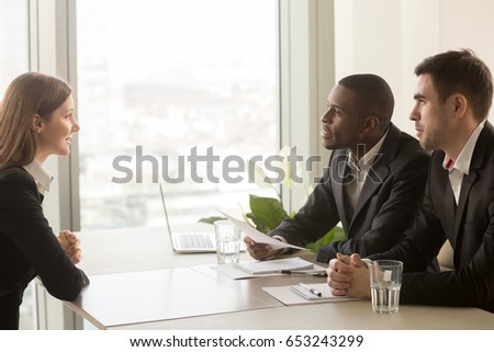 Side view of female applicant introducing herself during job interview, talking about working experience, multiracial recruiters hr managers interviewing listening to candidate, considering cv resume