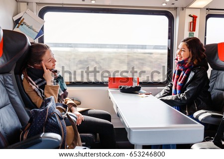 Two women Friends talk and laugh while traveling by train Royalty-Free Stock Photo #653246800