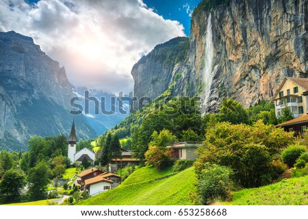 Amazing touristic alpine village with famous church and Staubbach waterfall, Lauterbrunnen, Switzerland, Europe Royalty-Free Stock Photo #653258668