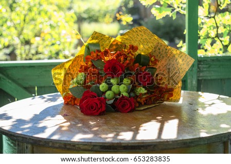 beautiful fresh red flowers in a bouquet on a terrace in summer on a sunny cheerful morning, festive warm background