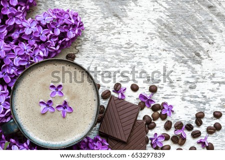 morning cup of coffee with purple lilac flowers and chocolate over white rustic wooden background. top view. flat lay